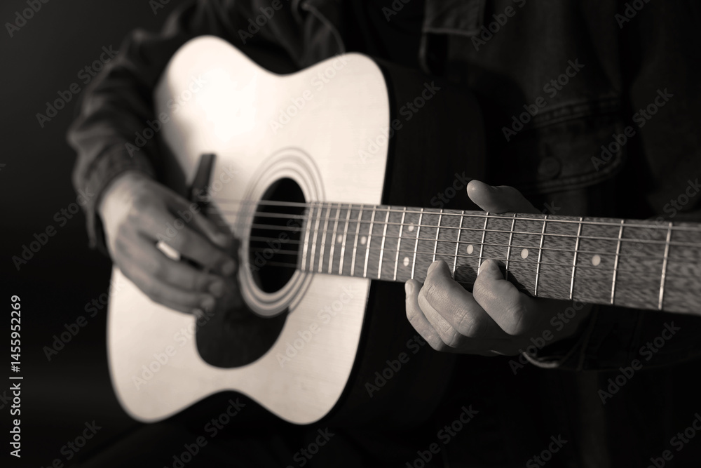 Fototapeta premium Man playing guitar in darkness, closeup. Black and white effect