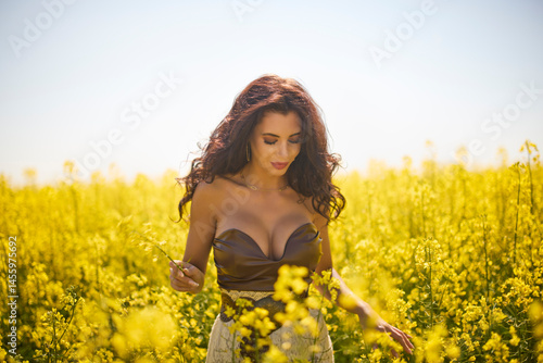 Obraz na płótnie beautiful woman posing in a field of blooming rapeseed w salonie