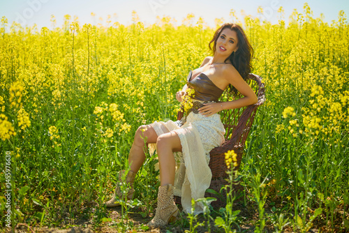 Obraz na płótnie beautiful woman posing in a field of blooming rapeseed w salonie