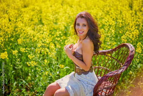 Obraz na płótnie beautiful woman posing in a field of blooming rapeseed w salonie