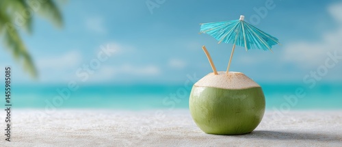 Obraz na płótnie Fresh coconut drink with a blue umbrella on a beach with turquoise sea and clear sky in the background. w salonie