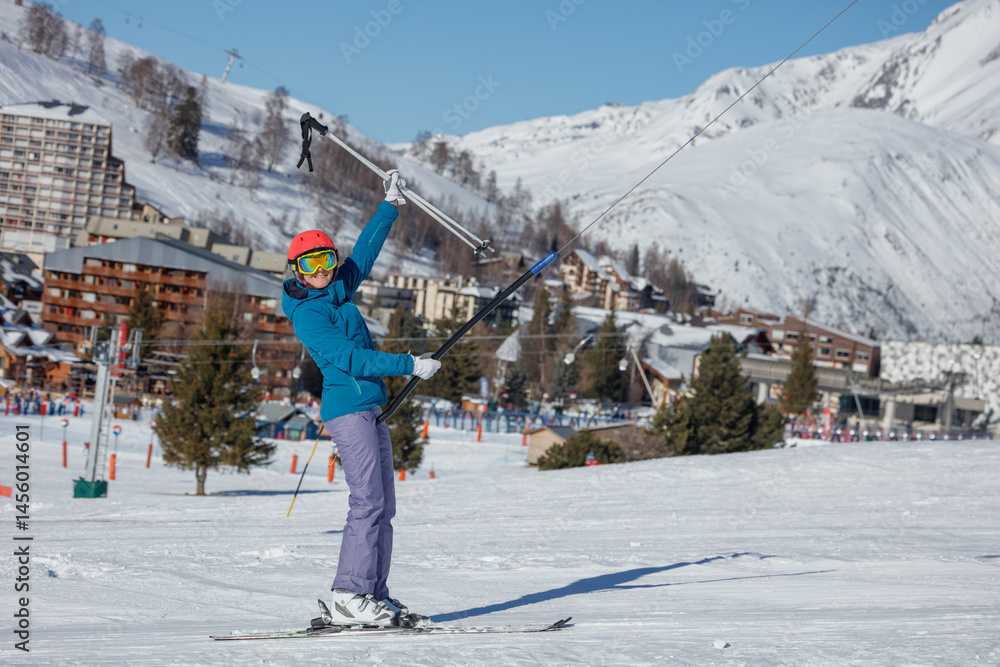 Happy skier woman on ski lift with mountain resort in backdrop