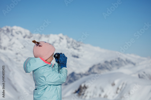 Obraz na płótnie Child girl exploring snowy mountain landscape with binoculars w salonie
