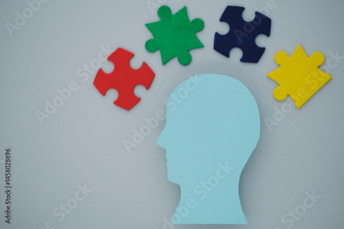 Silhouette of a blue head with colorful puzzle pieces on gray background. The concept of mental health and the formation of an inclusive society. top view
