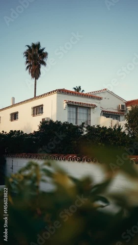 Charming Spanish villa at golden hour with tiled roof and palm tree peaceful Mediterranean vibes. 