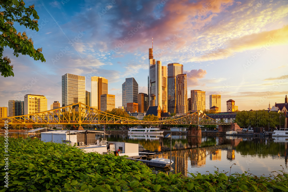 Golden sunrise view of the skyline of Frankfurt am Main, Germany, with banking skyscrapers, Eiserner Steg Bridge and River
