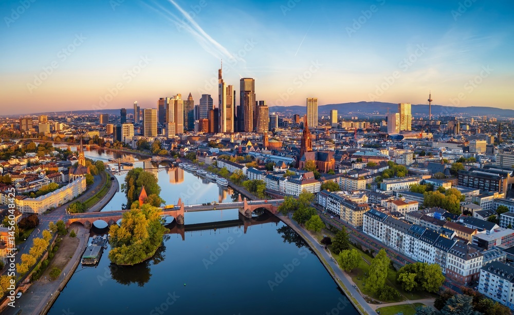 Panoramic aerial view of the skyline of Frankfurt am Main, Germany, with golden sunrise light reflecting on the office skyscrapers