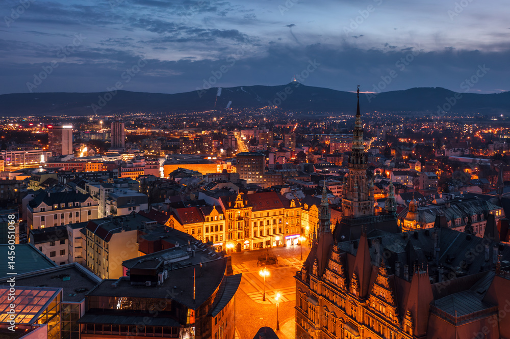 Evening skyline cityscape of Liberec, Czech Republic. Panoramic aerial view of the old town (staré město): main square and city hall at night with Ještěd mountain in the background