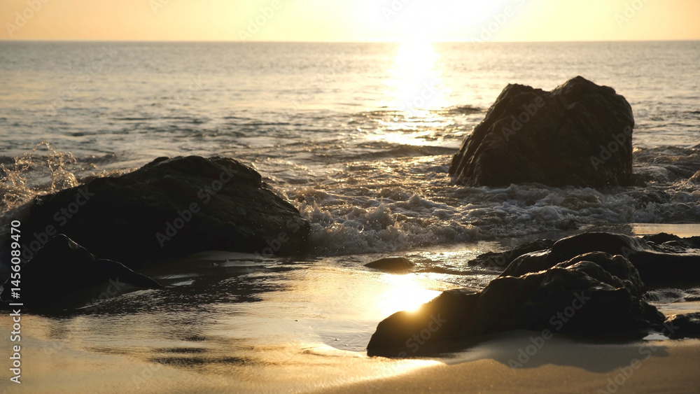 Fototapeta premium The sea, rocks and water wave with a beautiful sunset sky