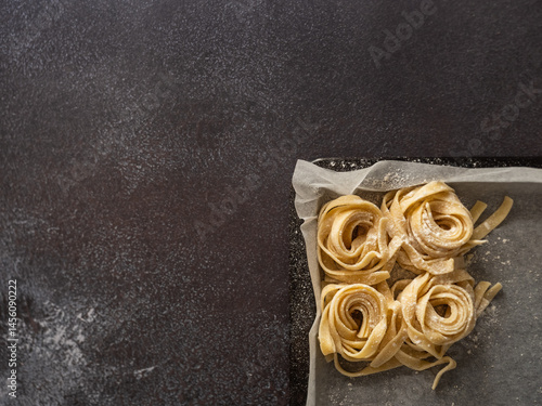 Pasta nests on a kitchen tray with baking paper. Copy space flat lay.