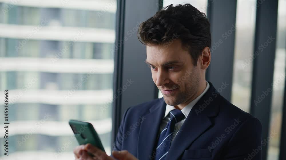 Smiling entrepreneur reading sms standing by window business center closeup.