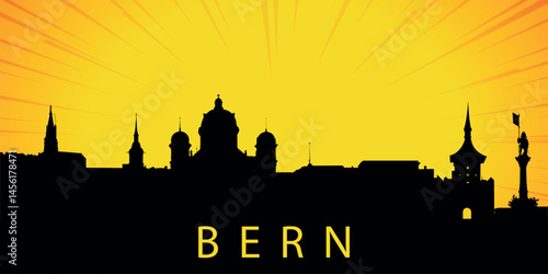 A silhouette of the skyline of Bern, Switzerland against the backdrop of the sunset. The sun is low above the horizon, emitting orange-yellow light with rays that diverge upward.