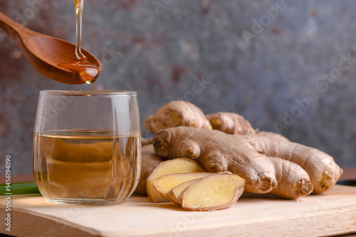 Cup of tea with ginger root on a wooden table, Ginger tea with and honey on a gray background.