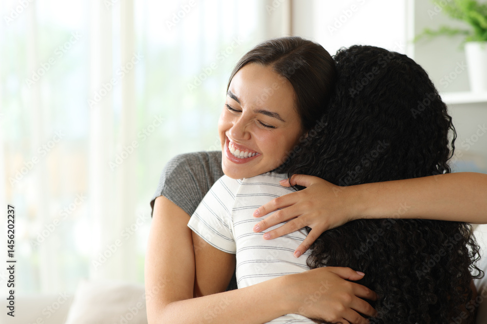 Happy woman hugging a friend in a house Happy woman hugging a friend in a house