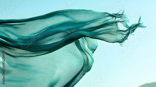 Turquoise silk scarf undulating against a serene, pale blue sky background