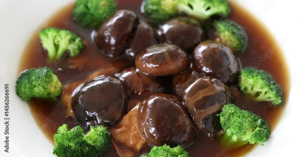 Hand held shake video of Chinese festive Braised Shiitake Mushrooms With Broccoli and bean curd in white dish being served Hand held shake video of Chinese festive Braised Shiitake Mushrooms With Broccoli and bean curd in white dish being served