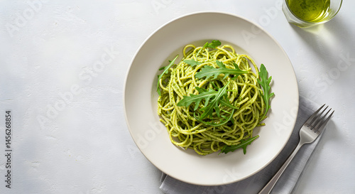 Delicious Spaghetti Served with Pesto Sauce and Fresh Arugula on White Plate