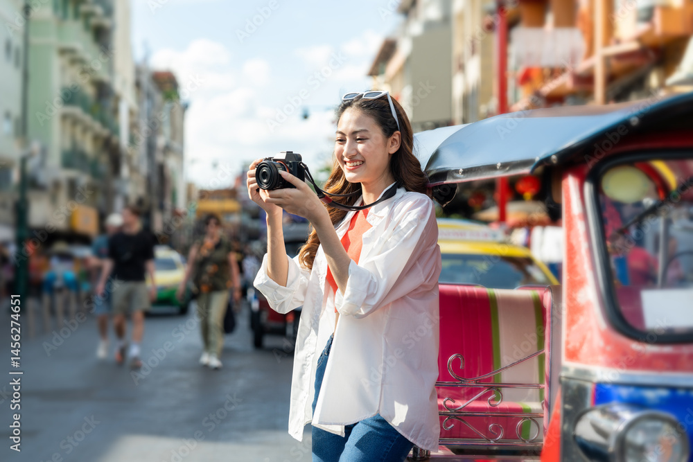 Obraz premium Young Asian woman traveling backpacker in Khaosan Road outdoor market in Bangkok Thailand. Happy female tourist walking in the downtown street traditional market
