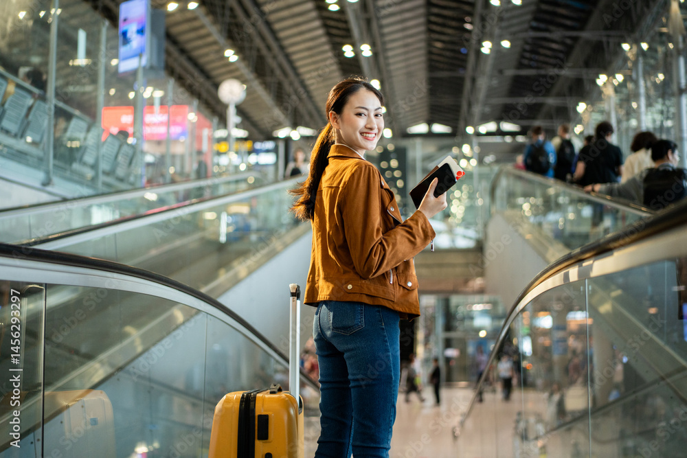 Obraz premium Portrait of confident young businesswoman smiling at camera ready traveling business trip with holding passport with ticket boarding pass and smartphone at the international airport terminal.