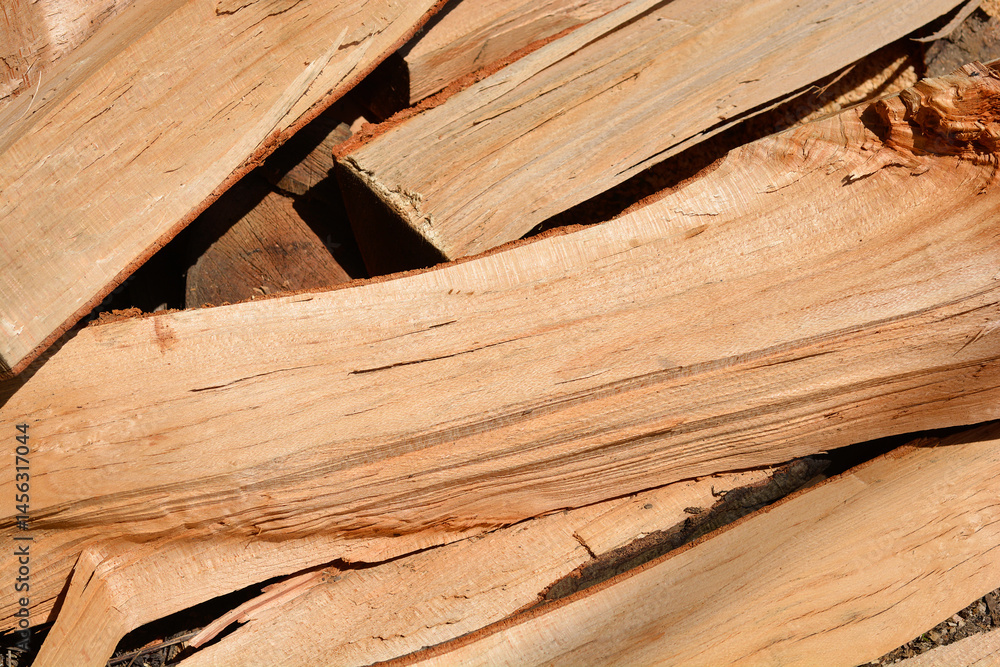 A close-up shows a jumbled stack of light brown firewood pieces with visible wood grain
