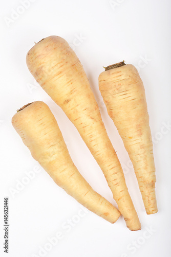 Three pale beige parsnips are arranged diagonally on a white surface