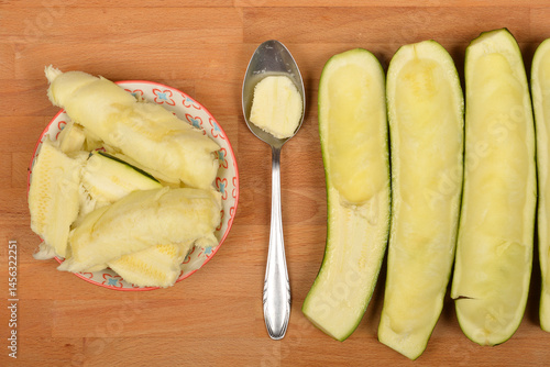 Obraz na płótnie Halved and scooped-out zucchinis are arranged with removed pulp in a bowl and on a spoon on a wooden board w salonie