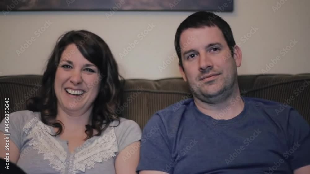 Bored spouses watching movie feeling disinterested at home. Man woman laughing Bored spouses watching movie feeling disinterested at home. Man woman laughing