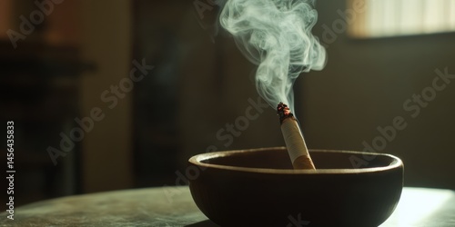 Obraz na płótnie Lit cigarette in wooden ashtray with dark background and warm side light highlighting the rising spiral of smoke. w salonie