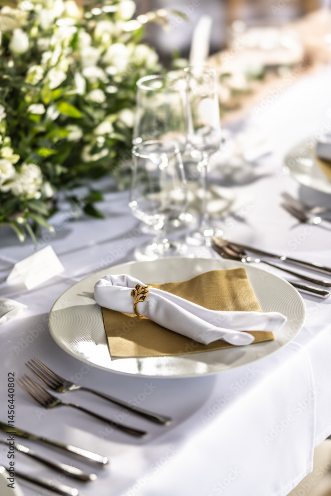 Fototapeta premium A wedding table covered with a white tablecloth, decorated with flowers, candles, glasses and cutlery