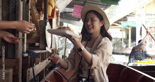 Asian tourist woman taking picture and smile and travel along the canel Damnoen Saduak Floating Market ratchaburi,Thailand