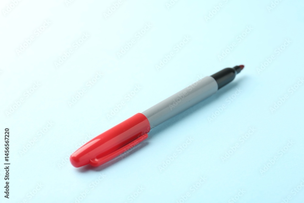 One red marker on light blue background, closeup. Space for text One red marker on light blue background, closeup. Space for text