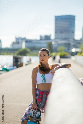 Foto Mulatto girl walks along the embankment with a skateboard and a volleyball, a mu