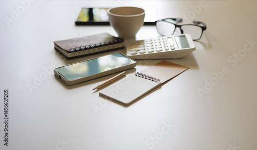 office desk table with mobile, calculator and notebook with accessories for work on white table