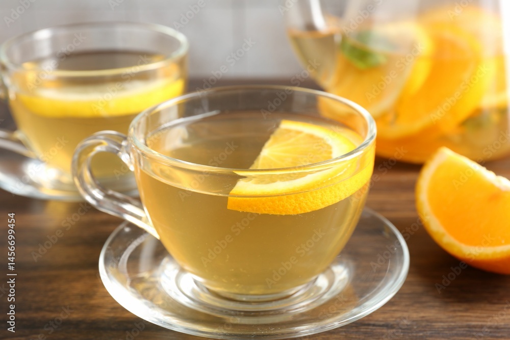 Aromatic fruit tea with orange and lemon in glass cups on wooden table, closeup Aromatic fruit tea with orange and lemon in glass cups on wooden table, closeup