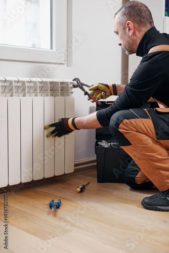 Obraz na płótnie Central heating mechanic and handyman fixing home radiator, gas crisis and seasonal issues. w salonie