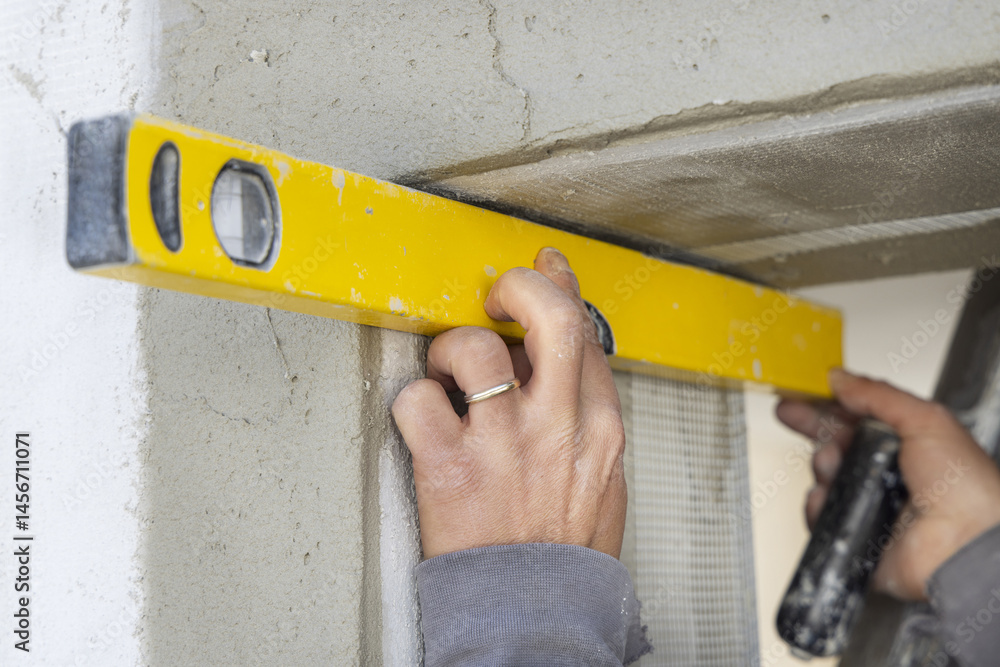 Craftsman uses a yellow level to control a house doorway hands closeup. Construction process