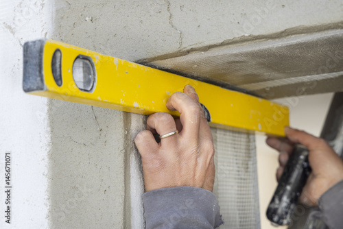 Obraz na płótnie Craftsman uses a yellow level to control a house doorway hands closeup. Construction process w salonie