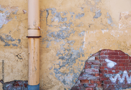 Фотография Weathered wall with a rusty metal drainpipe and worn textures