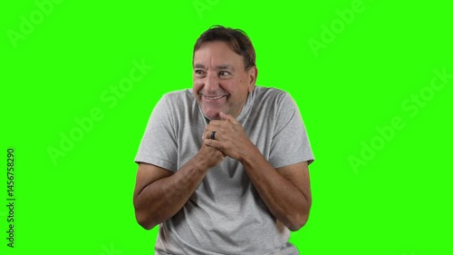 Sinister man in gray shirt rubs his hands together mischievously, as if plotting something sneaky or clever. Green screen background allows for easy compositing.  	
