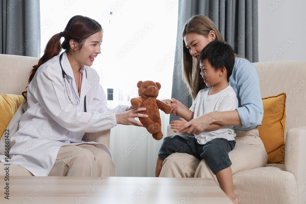 Smiling doctor giving teddy bear to happy child sitting with his mother during home healthcare visit or premium clinic ,Warm, caring interaction, highlighting pediatric care, compassion, and emotional Smiling doctor giving teddy bear to happy child sitting with his mother during home healthcare visit or premium clinic ,Warm, caring interaction, highlighting pediatric care, compassion, and emotional