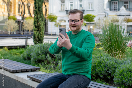 Fotografie A jovial Caucasian man in a vivid green sweater captures digital spring joy, emb