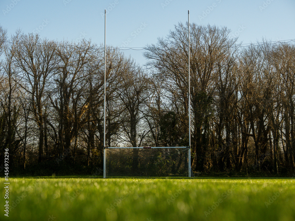 Tall goalposts in a training field for rugby, camogie, hurling, Gaelic football which are National sports of Ireland. Nobody on the grass, Warm sunny day.