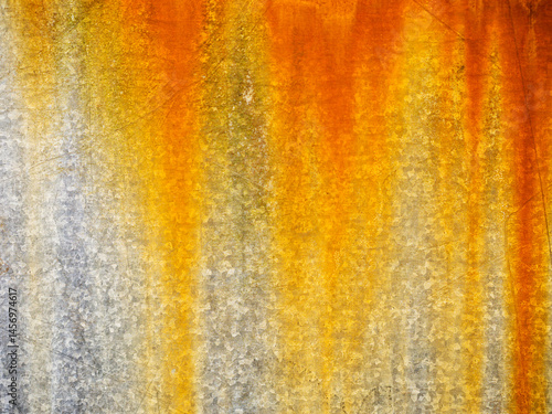 A rusty metal surface with a yellowish-orange hue. The surface appears to be weathered and worn, giving it a sense of age and history