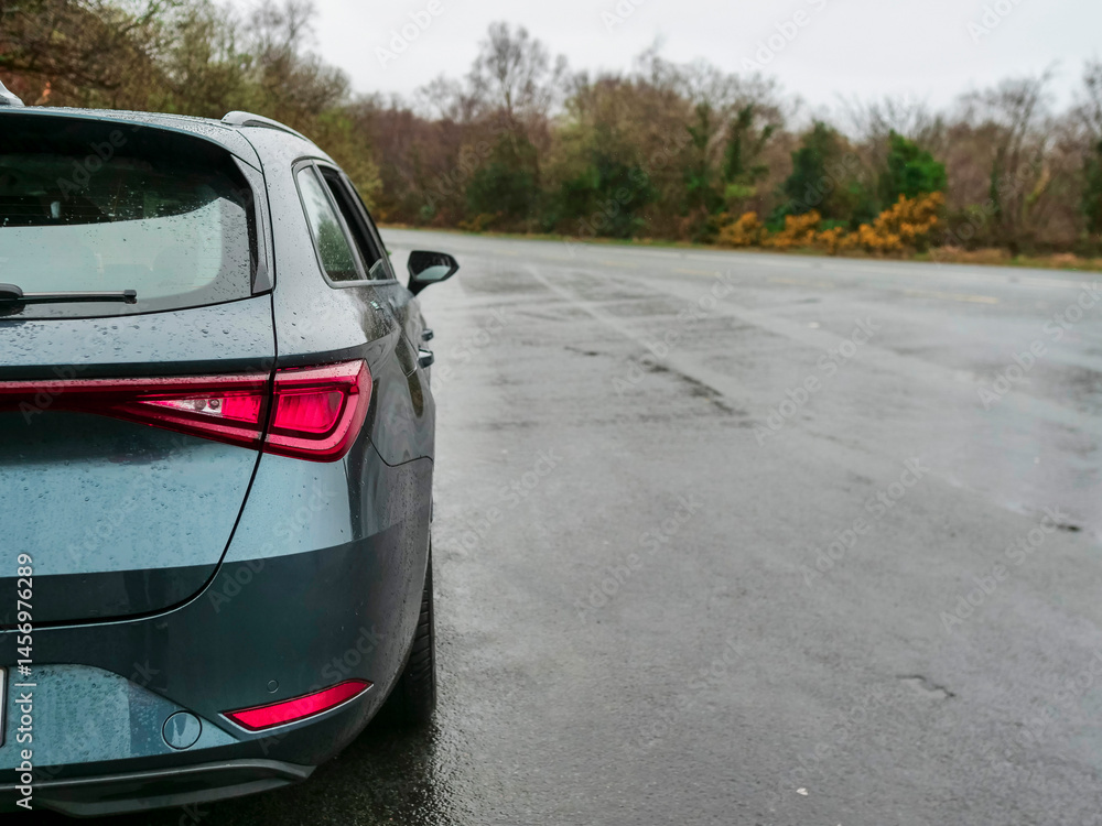 Light green car parked off road which is wet after a rain. Take a break while driving concept. Safety and security. Travel and tourism.