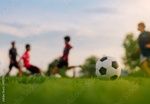 Action sport outdoors of kids having fun playing soccer football for exercise in community rural area under the twilight sunset sky.