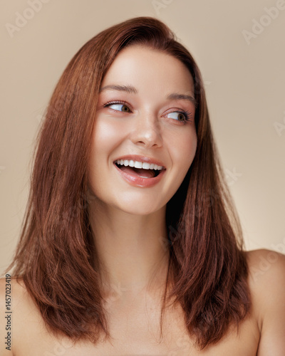 Obraz na płótnie Smiling redhead beauty model with radiant skin looking to the side in soft studio light. Great for skincare, beauty, and healthy lifestyle promotional use. Trendy and minimal look. w salonie