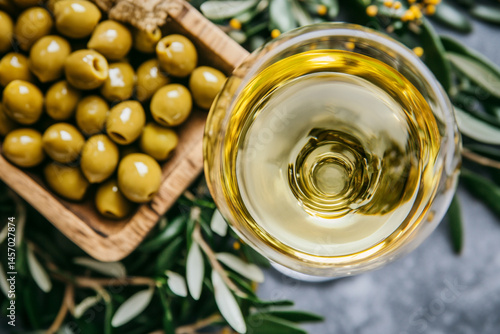 Obraz na płótnie Top View Showcases a Glass of White Wine Beside Green Olives on a Rustic Wooden Table Accompanied by Olive Leaves w salonie