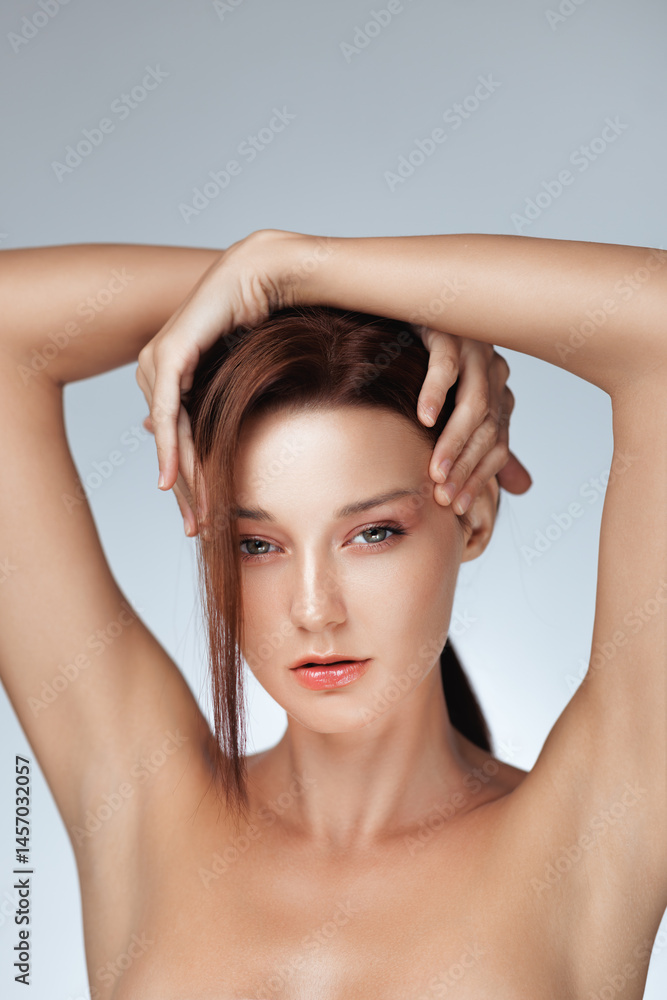 Confident young woman with glowing skin, nude makeup, and lifted arms posing with elegance in a skincare and beauty concept photo - ideal for anti-aging, cosmetics, or wellness campaigns.