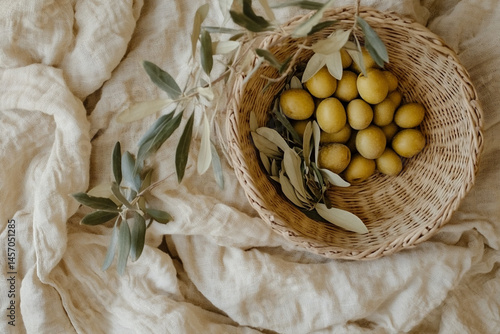 Obraz na płótnie Basket of Olives Resting on a Textured Fabric With Olive Leaves Arranged Around It in a Top View Setting During Daylight w salonie