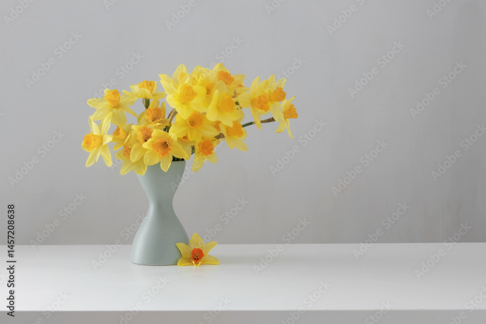 yellow spring flowers in green vase on white background